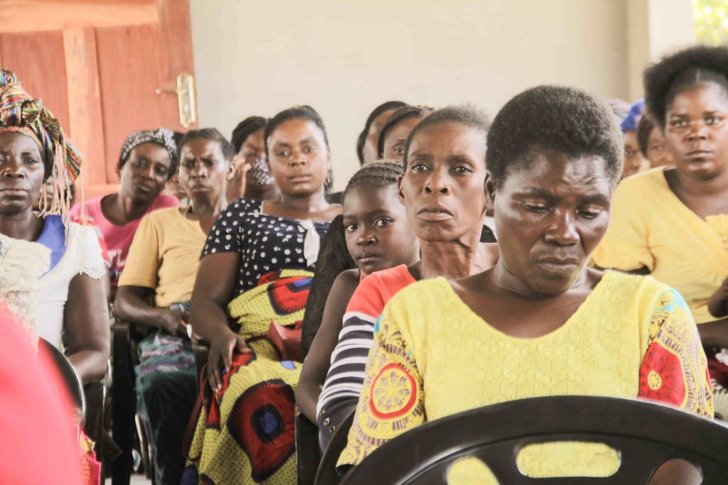 Girl sitting amongst African women in her community.