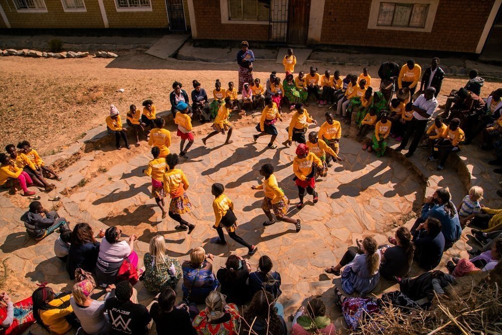 Kids in Zambia running in a circle and performing a program for expedition team members.