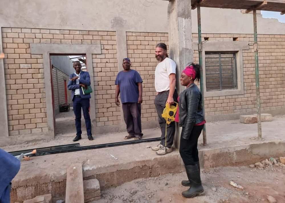 Josephine, Phillip, the construction manager, and the building inspector standing in front of construction site.