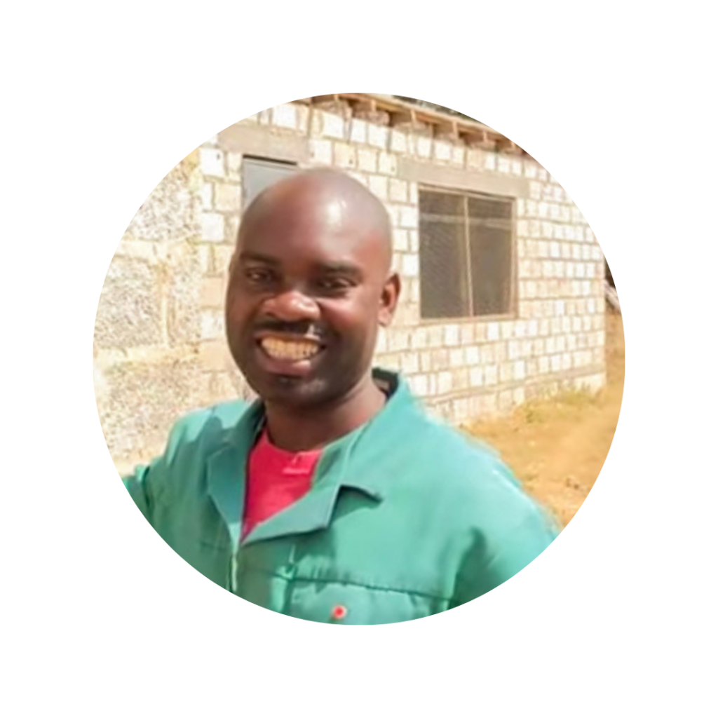 Zambian man smiling in front of a chicken coop.