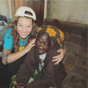 Volunteer kneeling and hugging a Zambian grandmother on the floor.